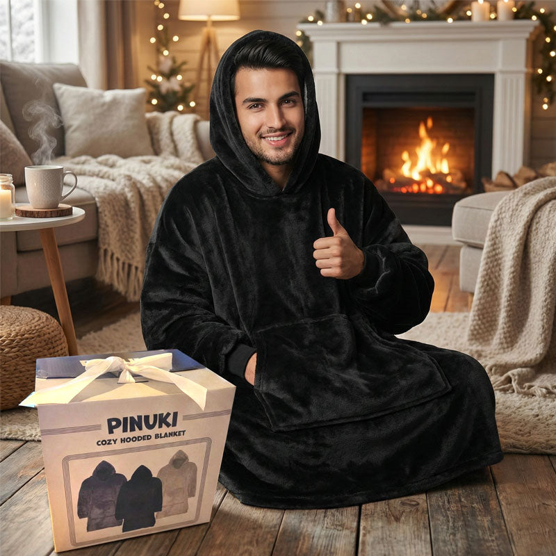 גבר יושב בסלון ליד אח בוערת לבוש בפינוקי שחור לצד אריזת המתנה המקורית