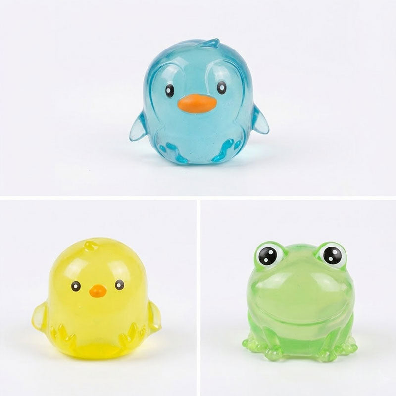 סט בובות מעיכה סקווישי שקופות בצורת פינגווין כחול, אפרוח צהוב וצפרדע ירוקה, מוצגות בתוך קופסת תצוגה ורודה וכבודדות